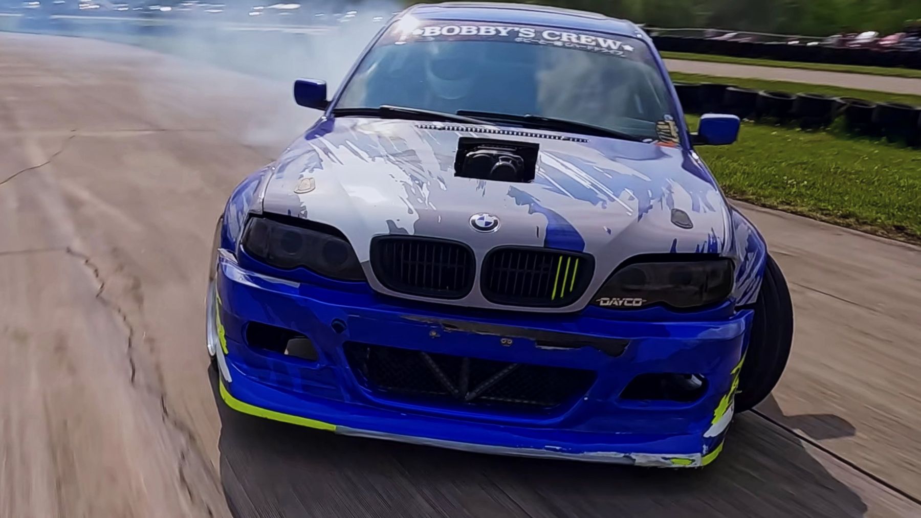 Head-on FPV shot of a blue BMW drifting toward the camera