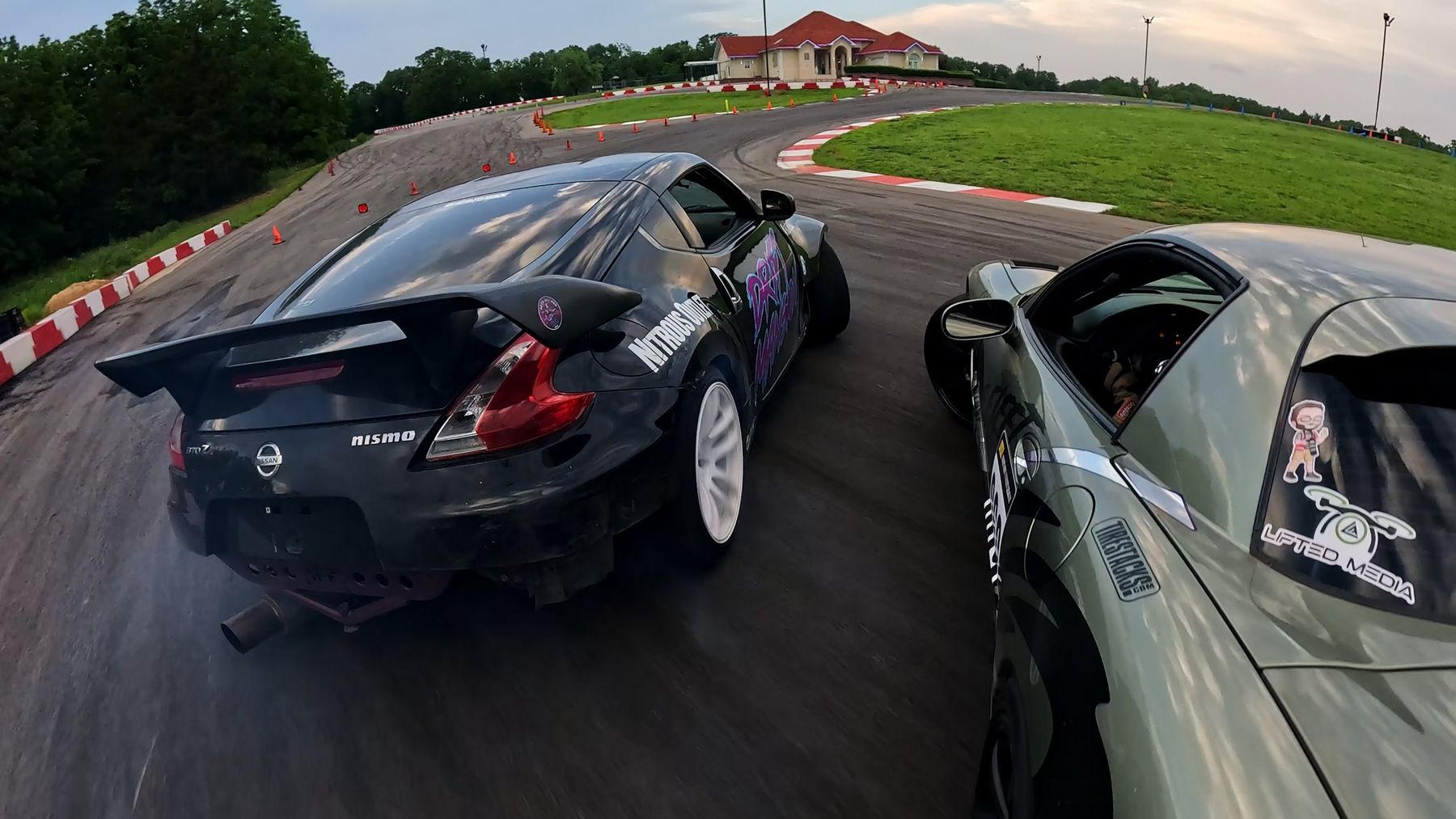 Chase-cam view of two Nissan 370Zs drifting through a corner